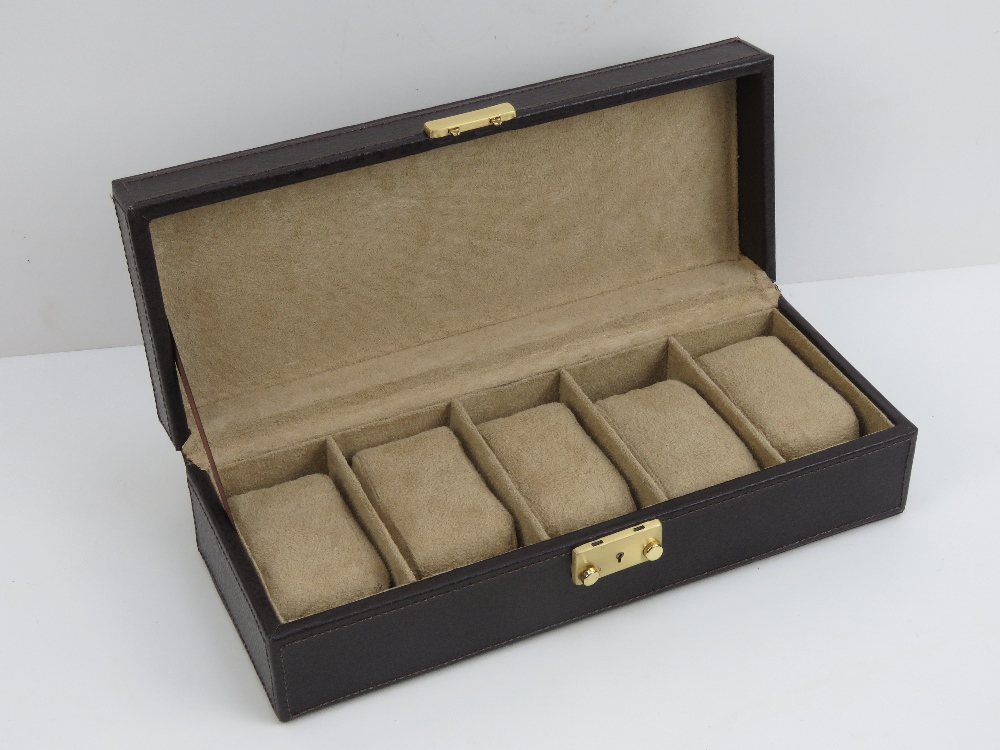 A contemporary brown leather watch box opening to reveal compartments for five watches,