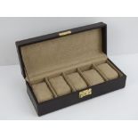 A contemporary brown leather watch box opening to reveal compartments for five watches,