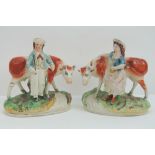 An opposing pair of Staffordshire figurines each having cow upon and standing 17cm high, a/f.