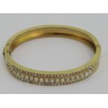 An Edwardian yellow metal and seed pearl bangle, two seed pearls deficient, no apparent hallmarks,