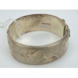 A HM silver bangle having leaf engraving to front,