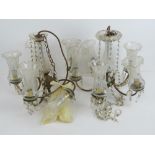 A pair of brass fire sconce chandeliers with light shades.