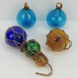 Four coloured glass fishing floats together with a vintage split cane fishing rod.