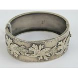 A late Victorian HM silver bangle having raised floral decoration to front,
