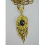 A yellow metal pendant having large central garnet cabachon and raised foliate decoration upon,