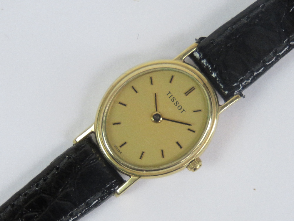 A 9ct gold ladies Tissot wristwatch having yellow metal hands and batons to the oval dial,