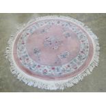 A circular woollen rug having oriental pattern upon in pink ground, 126cm diameter, a/f.