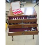 A three drawer cutlery cabinet raised over four shaped legs and containing full compliment of