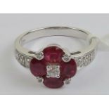 An 18ct white gold ruby and diamond ring having four oval cut rubies studded with diamonds in the