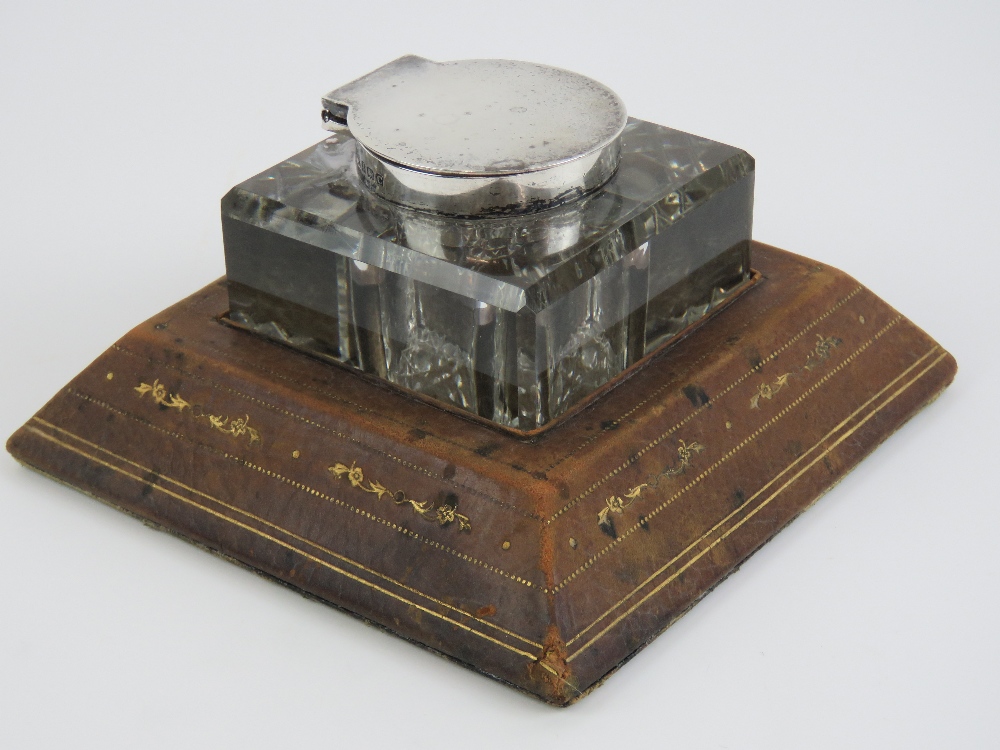 An Asprey desk inkwell having HM silver collar and lid with embossed tan leather base,