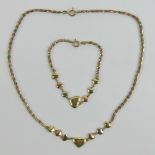 A 9ct gold suite comprising necklace and bracelet each having seven tri-colour hearts upon,