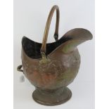A copper helmet coal scuttle having foliate decoration, swing handle over standing 52cm high.