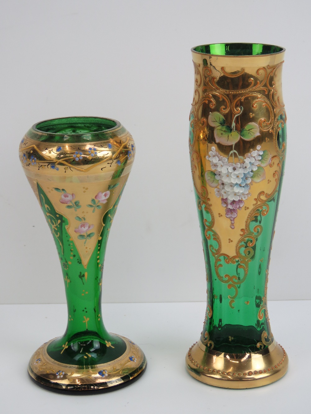 Two heavily gilded green glass Bohemian style vases having floral decoration throughout and