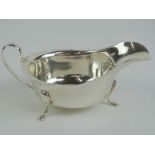 A HM silver sauce boat having pie crust edge and raised over three outswept feet,