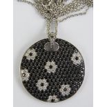 An 18ct gold pendant set with black sapphires and diamonds in a floral pattern, 3cm dia,