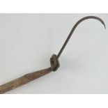 A vintage hay hook with long wooden pole handle.