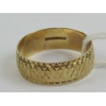 A 9ct gold band, hallmarked 375 having engine turned pattern throughout, size M-N, 1.8g.
