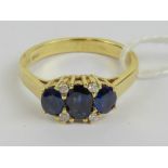 An 18ct gold sapphire and diamond ring having three graduated oval cut sapphires of royal blue hue,