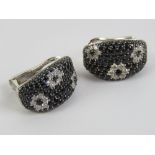A pair of 18ct white gold earrings set with black sapphires and diamonds in a floral pattern,