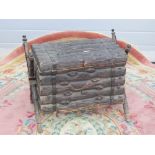 A lidded fireside log box in the form of a stack of logs raised over X shaped supports,