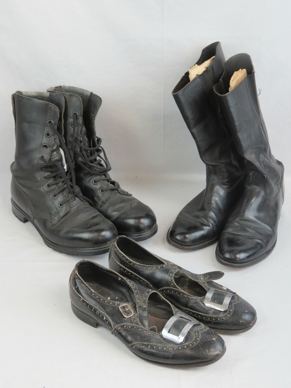 Two pairs of military boots together with a pair of buckled evening Highland shoes.