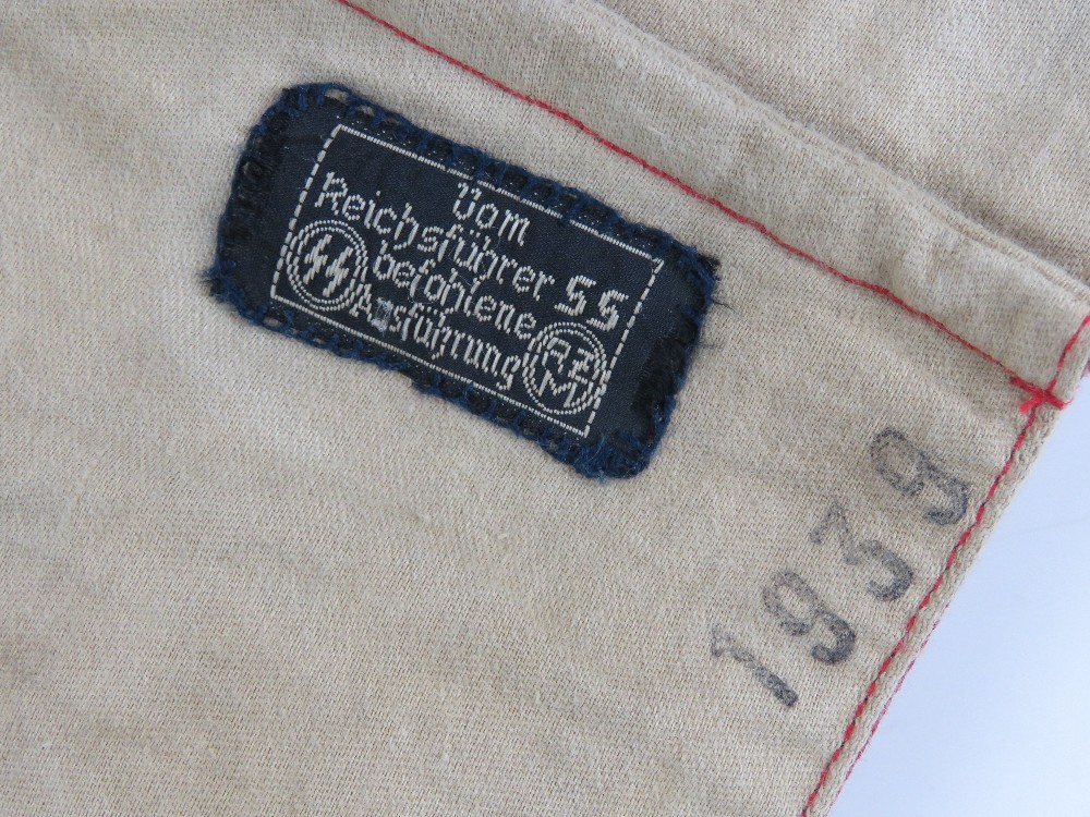 A WWII German swastika armband, SS issue having maker marks upon and labels with military stamps, - Image 2 of 4