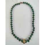A heavy malachite bead necklace, graduated beads having brass spacers and central brass hoop,