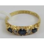 An 18ct gold sapphire and diamond carved head ring having three graduated round cut sapphires