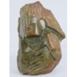 A 20th century moss agate carved figurine having oversized hands, one covering the angular face,