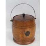 A c1930s oak ice bucket with swing handle and lid.