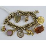 A HM silver gilt curb link charm bracelet with heart padlock clasp having six 9ct gold charms and