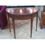 A 19th century mahogany demi moon fold over card table raised over tapering legs and opening to