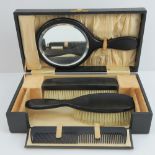 A vintage travelling dressing table set comprising hand mirror, and brushes in ebony,