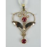 A delightful 9ct gold Edwardian open heart shaped pendant having two red round cut faceted stones,