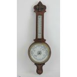 An Aneroid barometer and thermometer on carved oak back, measuring 79cm in length.