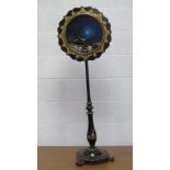 A delightful gilded and ebonised pole screen raised over adjustable column upon circular base with