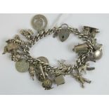 An HM silver curb link charm bracelet having heart padlock clasp and assorted silver and white