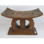 An early 20th century carved pierced and shaped African wooden stool, 49cm wide, 36cm high,