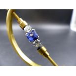 AN 18ct STAMPED CEYLON BLUE SAPPHIRE AND DIAMOND RING. THE CENTRAL SAPPHIRE IS A CORNER CLAW SET