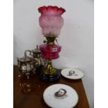 A VICTORIAN OIL LAMP WITH CRANBERRY GLASS RESERVOIR AND CONFORMING ETCHED SHADE AND BRASS DUPLEX