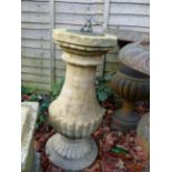 A COMPOSTITE STONE COLUMN SUPPORTING A SMALL BRASS SUNDIAL.