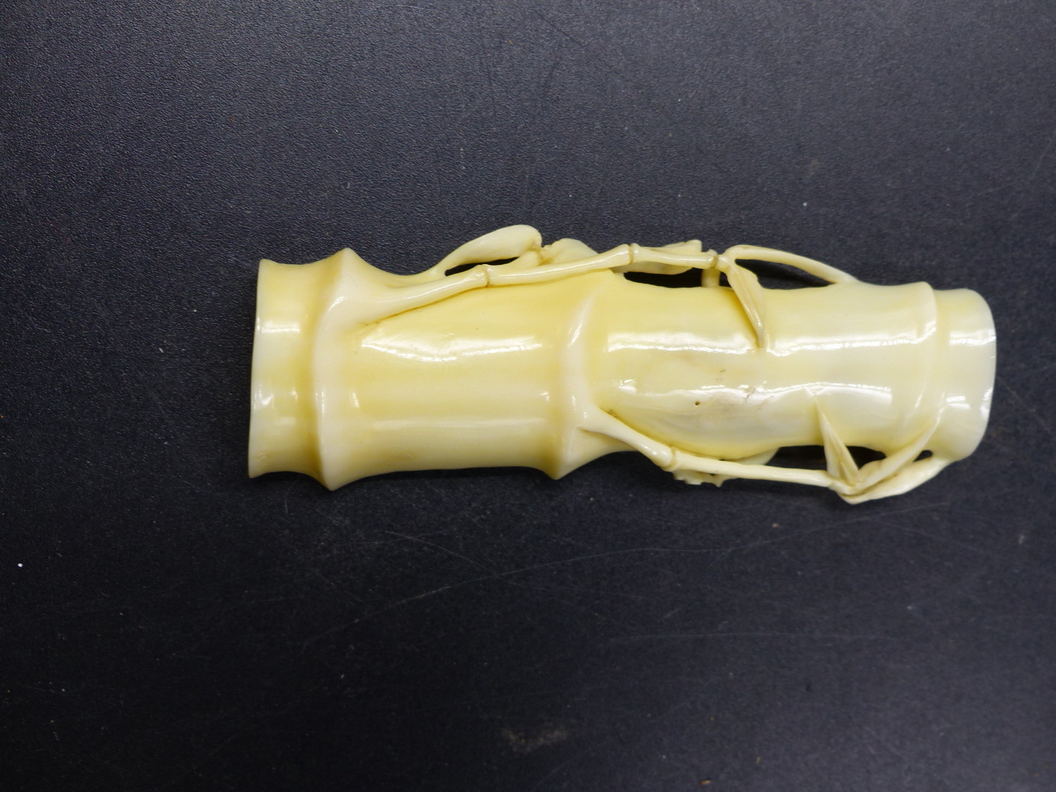 A JAPANESE MARINE IVORY OKIMONO CARVED AS A SPLIT SECTION OF BAMBOO CONTAINING A CONFRONTATION OF