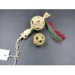 A CARVED IVORY CHINESE BALL WITHIN BALL PENDANT ON CHAIN, THE BALL Dia.5.5cms TOGETHER WITH