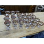 A SET OF TWELVE BOHEMIAN STYLE WHITE WINE GLASSES AND TWELVE CHAMPAGNE GLASSES, GILT BANDS WITH