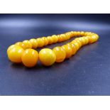 A CONTINUOUS GRADUATED ROW OF IRREGULAR SHAPED AMBER BEADS. WEIGHT 144grms.