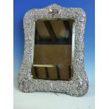 A VICTORIAN CHASED REPOUSSE DECORATED SILVER HALLMARKED MIRROR WITH A WOODEN BACK, DEPICTING