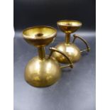 A PAIR OF DRESSER STYLE BRASS CANDLESTICKS, EACH WITH HANDLES ATTACHED TO THE HEMISPHERICAL BASES