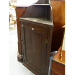 A GEORGIAN OAK WALL HANGING CORNER CABINET WITH SINGLE PANEL DOOR. W.63 x H.124cms.