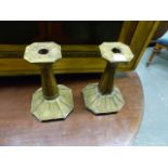 A PAIR OF ARTS AND CRAFTS BRASS CANDLESTICKS WITH CANTED SQUARE DRIP PANS AND FEET, THE BRASS PLATES