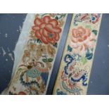 TWO CHINESE WHITE SILK SLEEVE EMBROIDERIES SEWN WITH FLOWERS, THE LONGER FEATURING PHOENIX AND THE